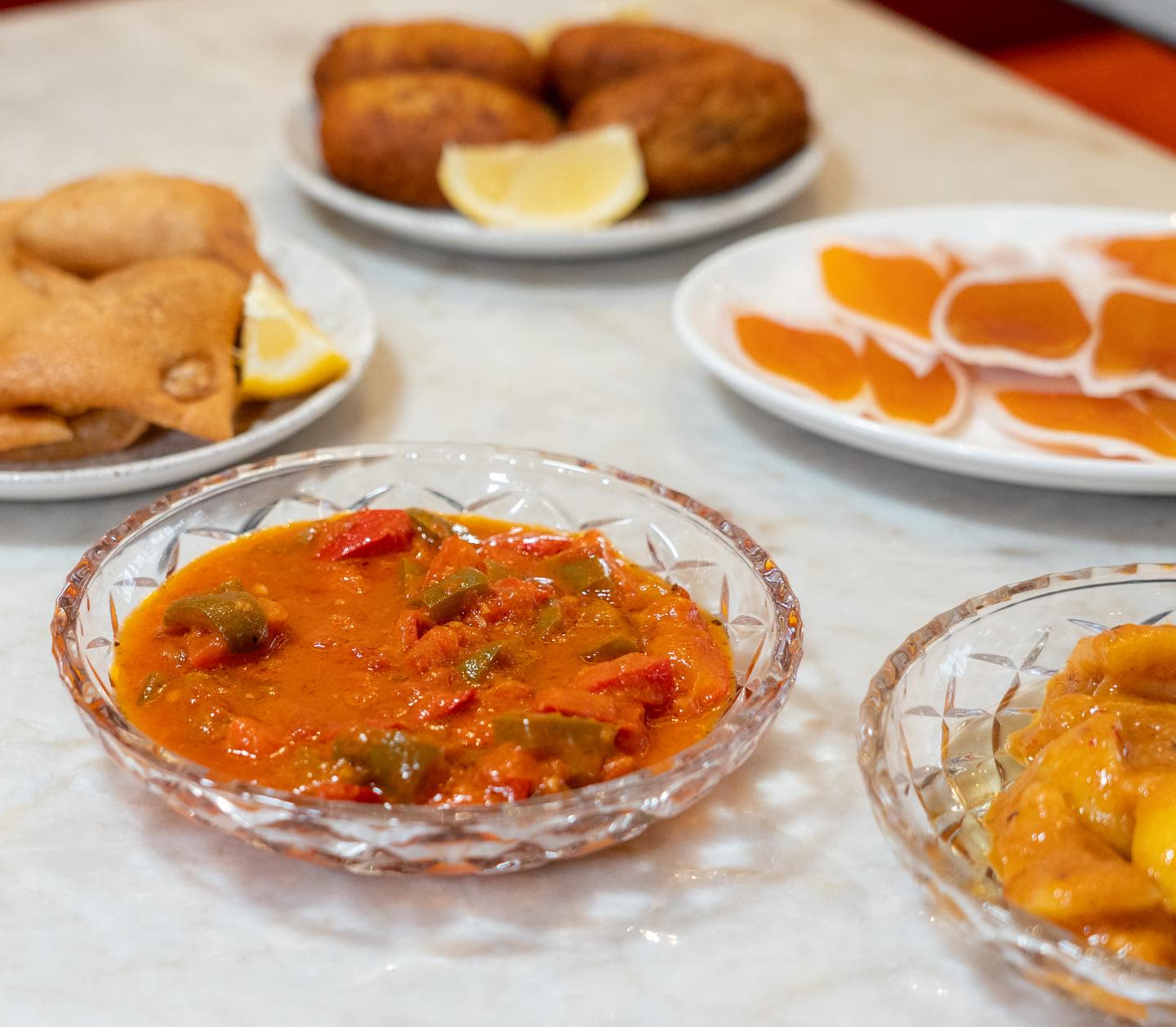 Plusieurs petits plats d'entrées tunisiennes servis dans des bols et des assiettes sur une table en marbre