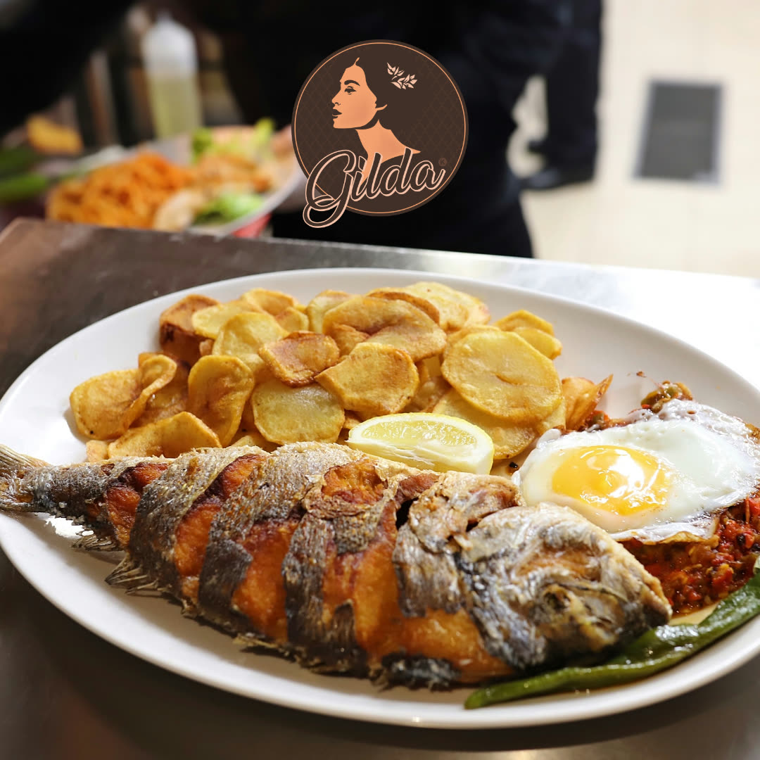 Un poisson entier frit servi avec des rondelles de pommes de terre et un œuf au plat