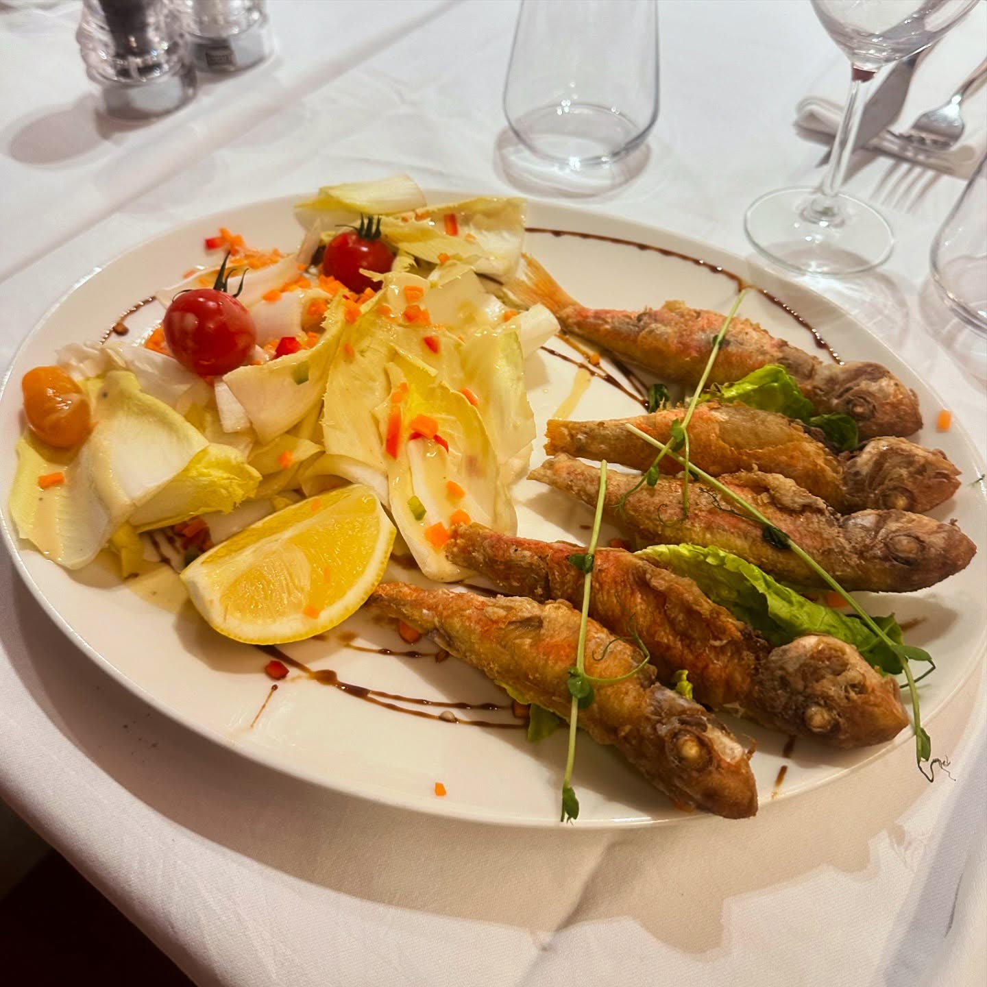 Un plat de poissons frits accompagné d'une salade composée et d'un quartier de citron