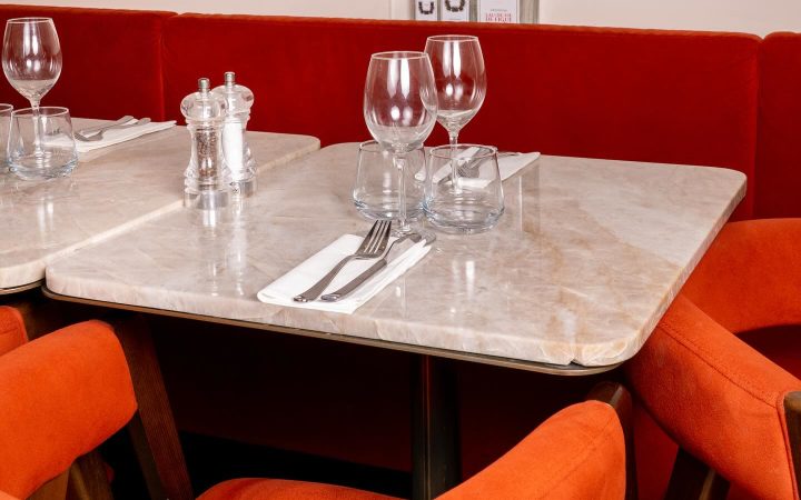 Une table en marbre dressée avec des verres, des couverts et des bouteilles en arrière-plan